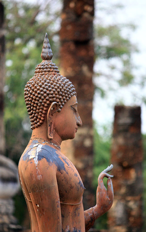 A weathered stone statue in a Japanese garden